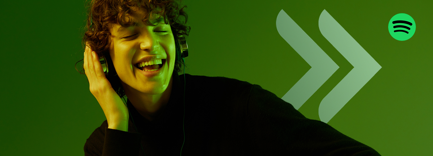 Młoda uśmiechnięta osoba otworzyła konto osobiste w UniCredit i słucha muzyki na słuchawkach poprzez Spotify Premium.